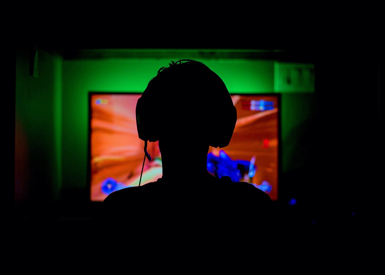 gaming $70 industry feature image of a person playing a video game in the dark.